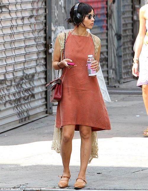 Zoe Kravitz walking in shorts and an orange top