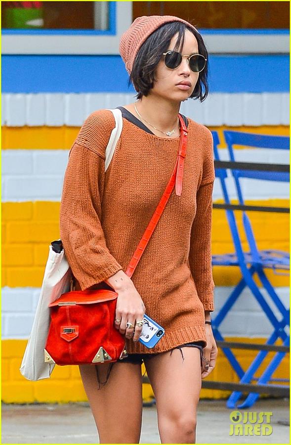 Zoe Kravitz walking in shorts and an orange top