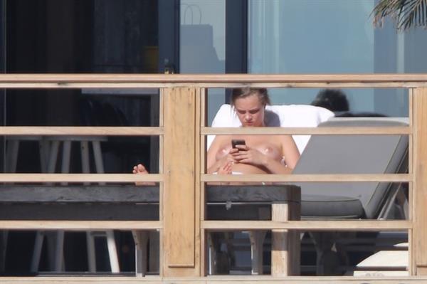 Cara Delevingne topless on a balcony