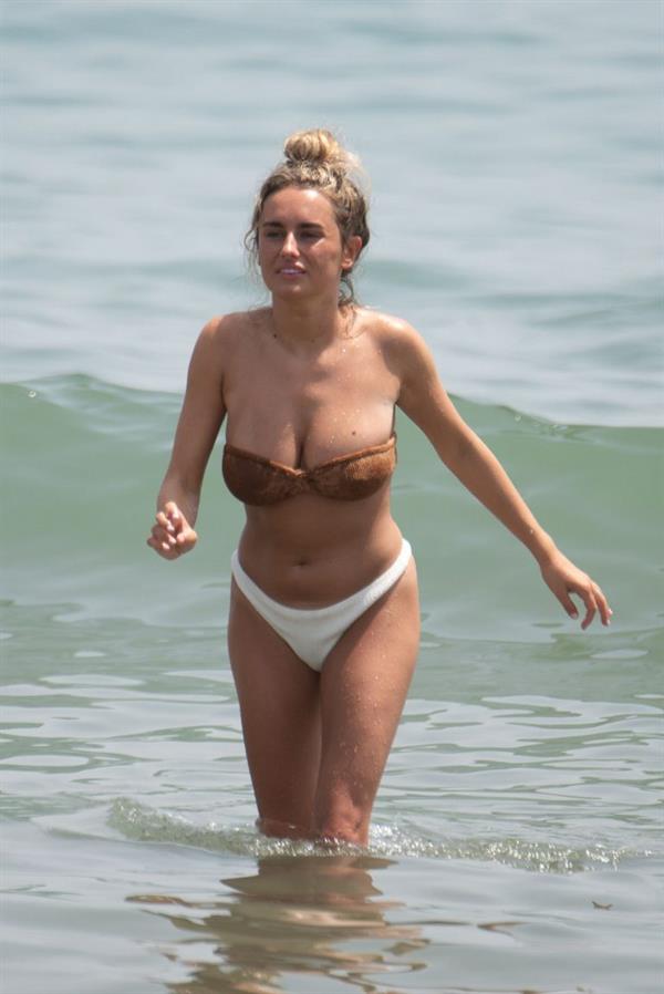 Amber Davies sexy boobs bouncing around in a loose bikini at the beach seen by paparazzi.

