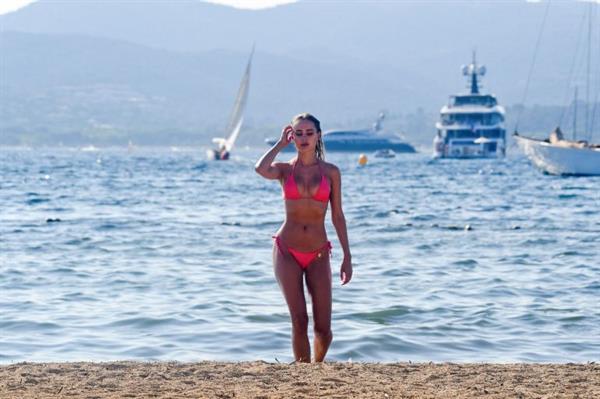Kimberley Garner sexy model body in a pink bikini at beach seen by paparazzi.




